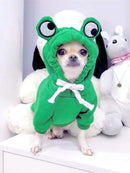 Cão de pequeno porte usando suéter verde com capuz em formato de sapinho, ideal para manter o pet confortável e estiloso nos dias frios.